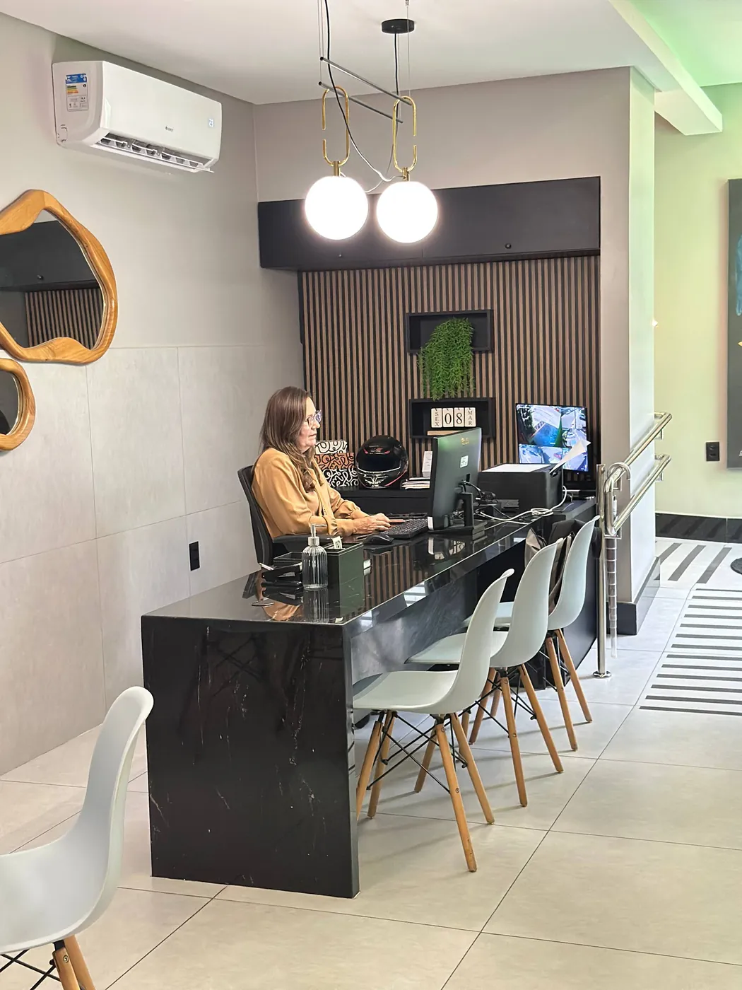 Recepção do My Office com bancada escura, espelho orgânico e quadro de chaves das salas