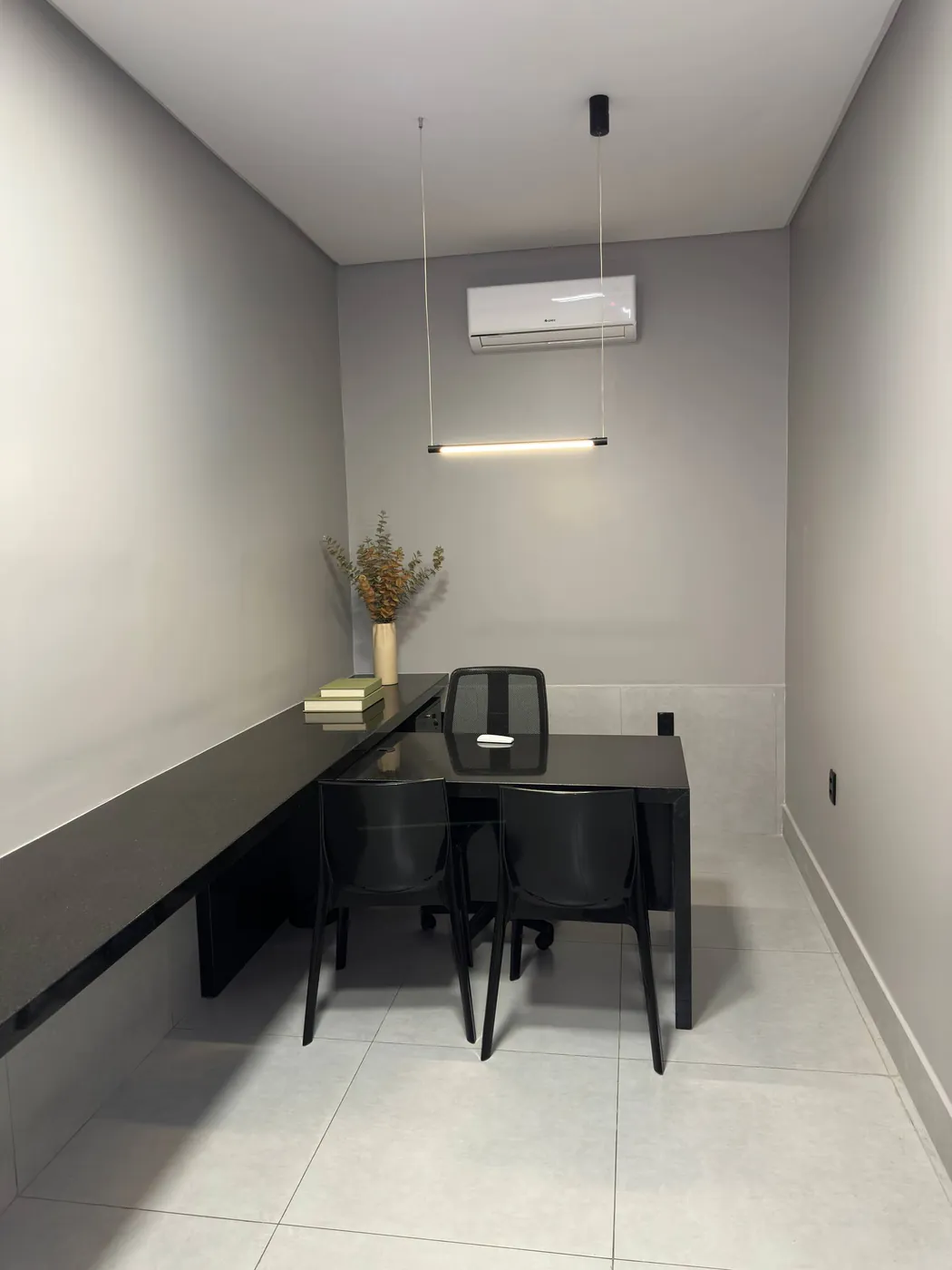Sala privativa do My Office com bancada preta, cadeiras, iluminação linear e ar-condicionado